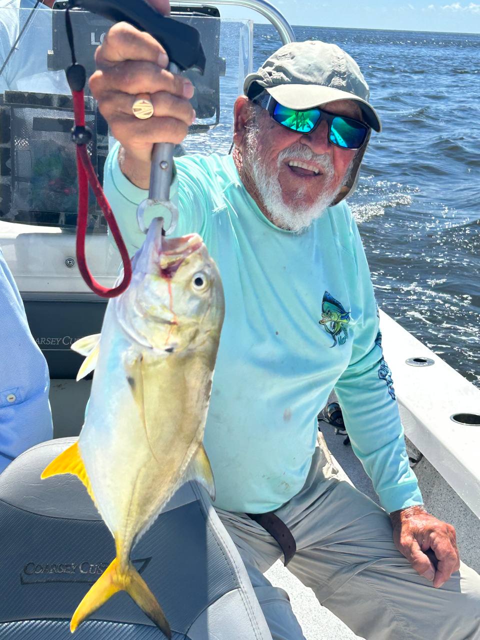 Close view of Captain Jim smiling while holding a yellow jack offshore