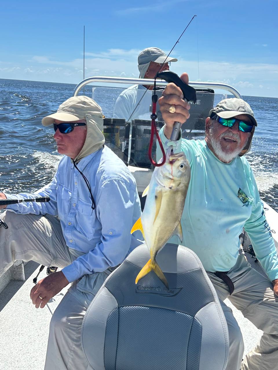 Captain Jim holding a yellow jack on a sunny offshore boat ride